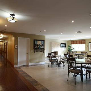 A spacious dining area with multiple tables and chairs adjacent to a hallway.