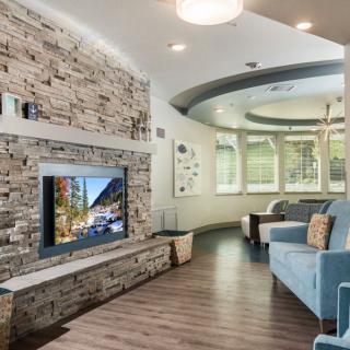 A modern living room featuring a stone accent wall with a mounted television, cozy seating area, and elegant wood flooring.