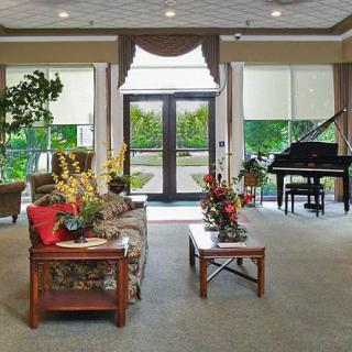 A well-decorated lobby featuring a grand piano, comfortable seating, and large glass doors leading outside.