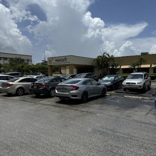 A busy parking lot at a shopping center under a cloudy sky.