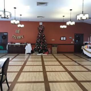 A spacious event room decorated for the holiday season, featuring a Christmas tree and festive decor.