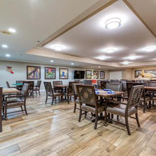 A spacious, well-lit dining area with wooden tables and chairs, decorated with artwork on the walls.