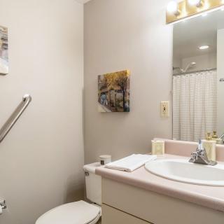 A small bathroom with a sink, toilet, mirror, and wall art.
