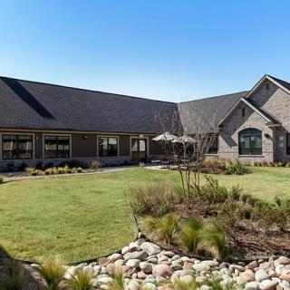 A spacious house with a well-maintained garden and lawn under a clear blue sky.