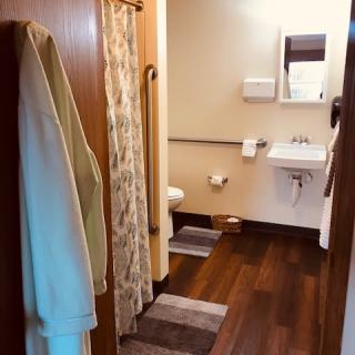 A cozy bathroom with wooden flooring, featuring a sink, mirror, and shower.