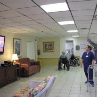 A nursing home common area with residents and a nurse.