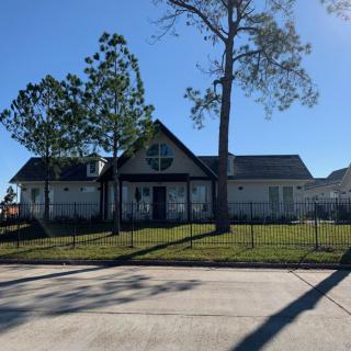 A suburban house with a fence and trees on a sunny day.