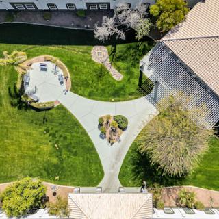 A beautifully landscaped garden with a circular seating area and well-maintained pathways, viewed from above.