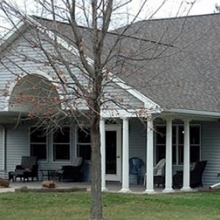 A charming residential house featuring a spacious porch and well-maintained lawn.