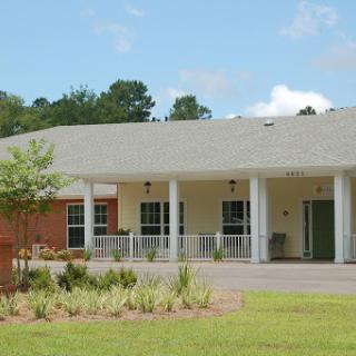 A modern healthcare facility surrounded by lush greenery on a sunny day.