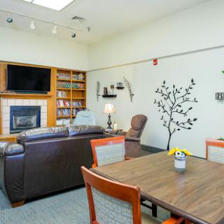 A cozy living space featuring a fireplace, bookshelves, and comfortable seating.