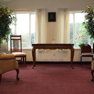 A cozy living room with elegant furniture, large windows, and lush greenery.