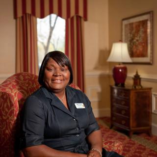 A woman smiling while seated in a living room setting.