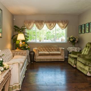 A cozy vintage-style living room with classic sofas, chairs, a window, and decorative elements.