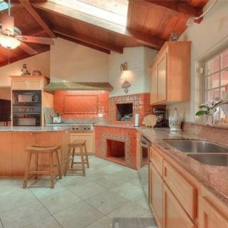 A spacious kitchen with a wooden ceiling and modern appliances, featuring a skylight that brightens the room.