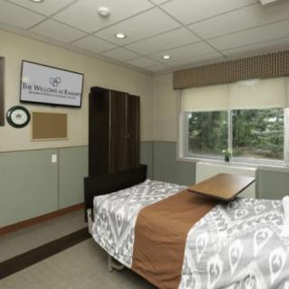 A well-equipped hospital room featuring a single bed with an overbed table and a wall-mounted television.
