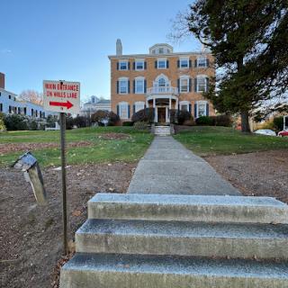 A historic building with a well-maintained front lawn and visible signage.