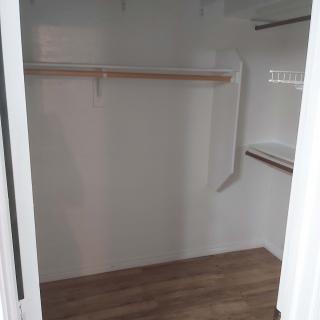 An empty walk-in closet with wooden flooring and built-in shelves.