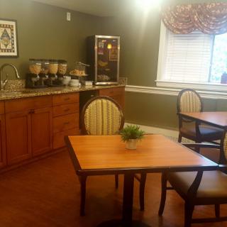 Cozy dining area with a coffee station, wooden tables, and striped chairs.