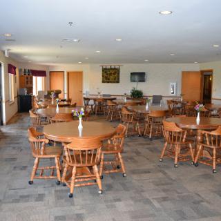 A spacious dining area featuring wooden tables and chairs, creating a welcoming environment.