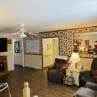 A cozy living room featuring armchairs, a TV, and various decorations.