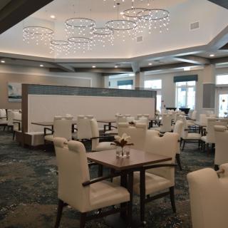 A modern and elegant dining area with chandeliers and neatly arranged tables and chairs.