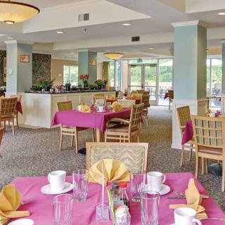 An elegantly set dining area with bright tablecloths and neatly arranged tableware.