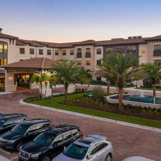 A view of an apartment complex with parked cars and palm trees at sunset.