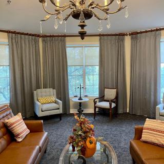 A cozy living room with leather sofas, armchairs, and a decorative coffee table under a chandelier.