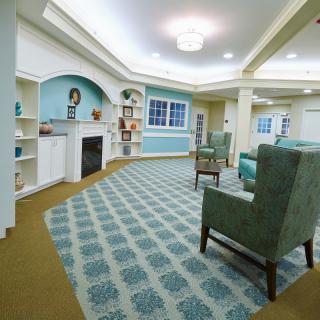 A cozy living room with elegant furniture, a fireplace, and patterned carpet.