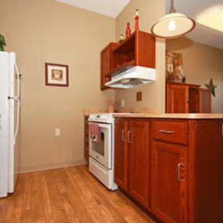 A cozy kitchen space with wooden cabinets, a white stove, and refrigerator.