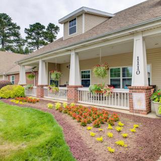 A suburban house with a front porch and well-maintained landscaping.