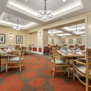 A spacious and elegantly designed restaurant dining area with tables and chairs arranged neatly under ornate chandeliers.