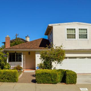 A suburban two-story house with a garage and well-maintained shrubs.