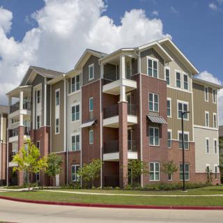 A modern multi-story apartment building with balconies and a mix of materials in its design.