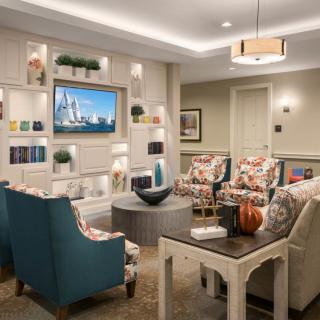 A modern living room with comfortable armchairs, decorative shelves, and a wall-mounted television.