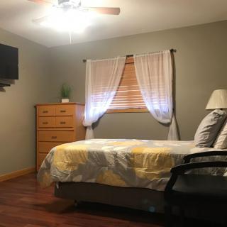A cozy bedroom with a neatly made bed, dresser, and wall-mounted television.