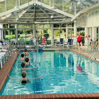 A group of individuals participating in a fitness class at an indoor swimming pool.