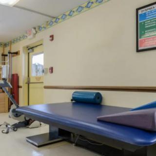 A physical therapy treatment room equipped with a padded table and exercise equipment.