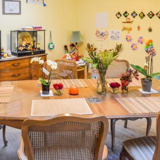 A cozy dining room with a wooden table, adorned with fresh flowers and colorful decorations on the walls.
