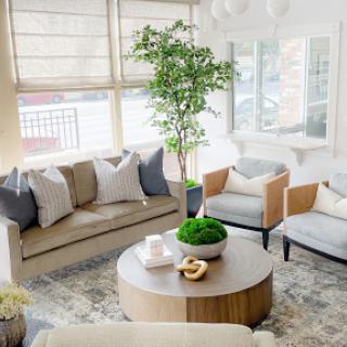 A stylish and modern living room featuring a cozy couch, armchairs, and a coffee table adorned with greenery.