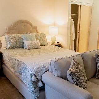 A cozy bedroom with a bed, sofa, and soft lighting.