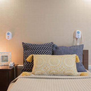 A cozy and modern bedroom with decorative pillows and a bedside table lamp.