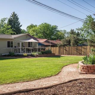 A well-maintained backyard with a green lawn, garden path, and a deck featuring a patio umbrella.