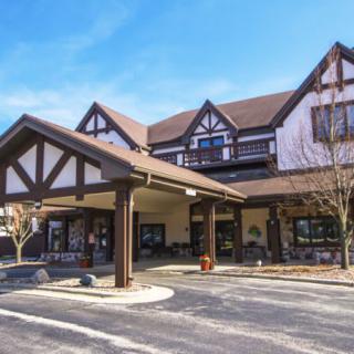 A tudor-style building with a covered entrance and adjacent parking lot.