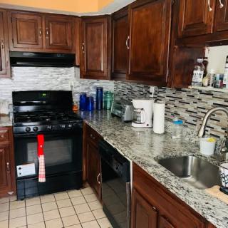 A kitchen interior with wooden cabinets, a granite countertop, and tiled backsplash.