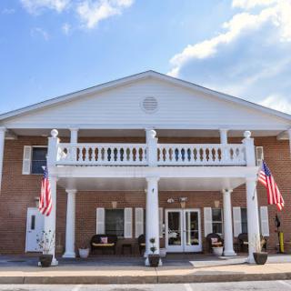 A welcoming residential building with a classic architectural style featuring white columns and American flags.