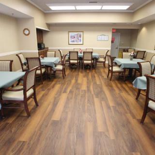 An empty dining room with neatly arranged tables and chairs on a wooden floor.