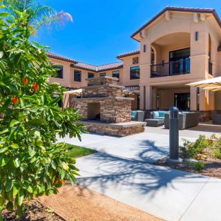 A sunny courtyard featuring a large fireplace in front of a modern residential building.