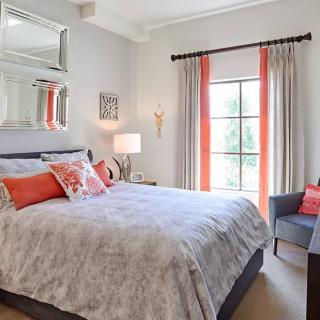 A cozy bedroom with modern decor featuring a bed, decorative pillows, and a window with curtains.
